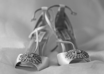 Close-up of white bridal heels decorated with sparkling crystal embellishments.
