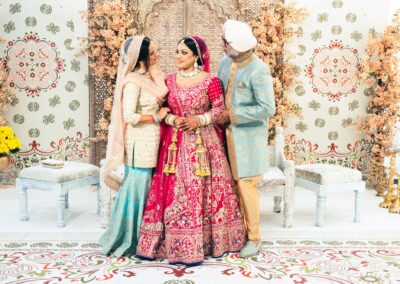 An Indian bride and groom with a guest stand in a beautifully decorated room.