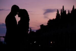 A silhouette of a couple embracing against a vibrant sunset sky.