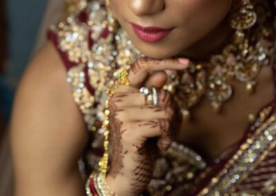 Bride looking up with confident expression showing detailed jewellery and mehndi art.