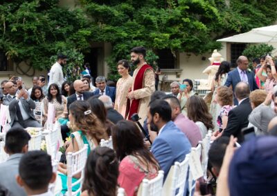 Guests seated and smiling while watching the wedding ceremony outdoors.