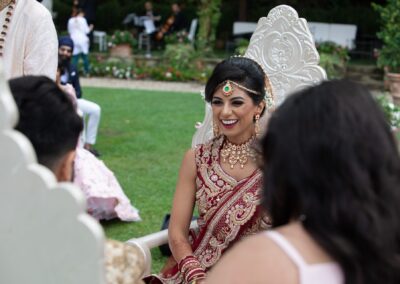 Guests clapping as bride and groom smile under floral mandap during Hindu wedding.