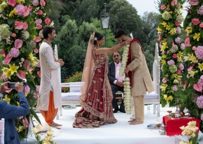 Bride placing floral garland on groom during traditional Hindu wedding ritual.