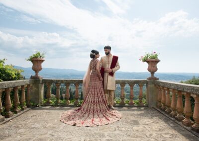 Bride and groom standing on balcony overlooking scenic mountain valley view.