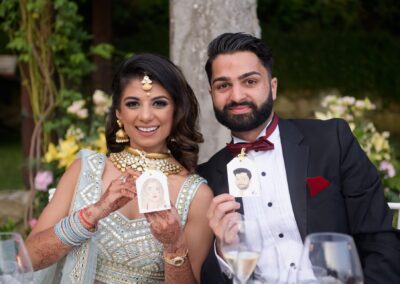 Bride and groom holding caricature tags of each other and smiling for a photo.