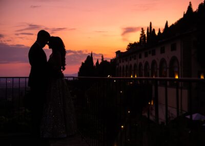 Couple sharing a romantic sunset moment in silhouette against a glowing orange sky.