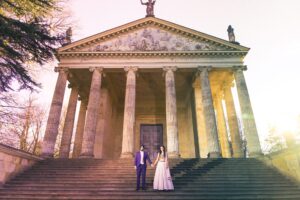 A couple stands on steps in front of a grand, columned building.