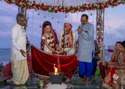 An Indian couple performs a wedding ritual with fire under a decorated canopy.