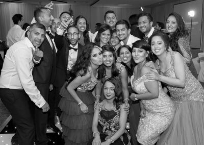 Group of wedding guests smiling and posing together during evening reception.