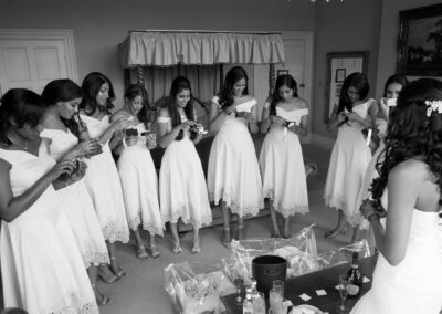 Black and white image of bridesmaids admiring their rings in a room.
