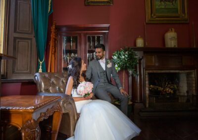 A bride and groom in a warm, traditional room, looking at each other.
