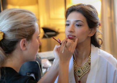 A close-up of a bride getting her lipstick applied by a makeup artist.