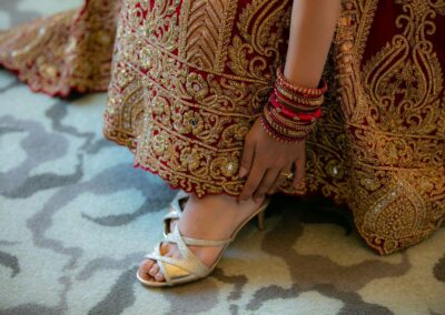 Close-up of a bride's foot in a golden sandal, with bangles on her wrist.