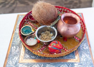 A close-up of a traditional Indian wedding tray with offerings including a coconut and diyas.