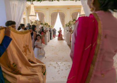 A long shot of an Indian wedding aisle with a flower girl and guests awaiting the bride.
