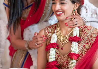 A mother lovingly adjusts her smiling daughter's traditional wedding jewelry.
