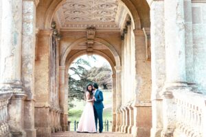 A couple embraces under a series of ornate stone arches.