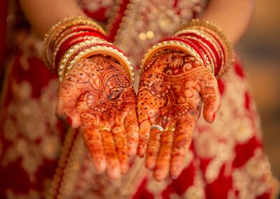 A close-up of a bride's hands adorned with intricate mehndi designs and bangles.