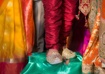A groom's ornate shoes and traditional pants, surrounded by colorful fabric.