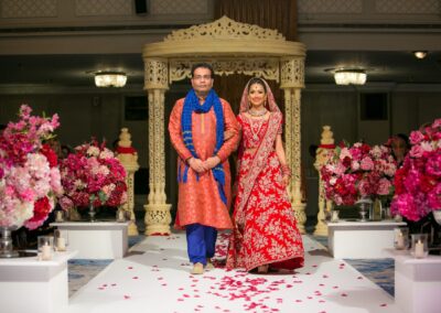 A bride and a man walk down an aisle adorned with rose petals.