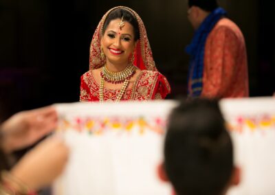 A smiling bride in traditional attire looks over a white cloth.