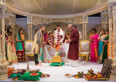 A wedding ceremony scene with a couple performing rituals, surrounded by guests.