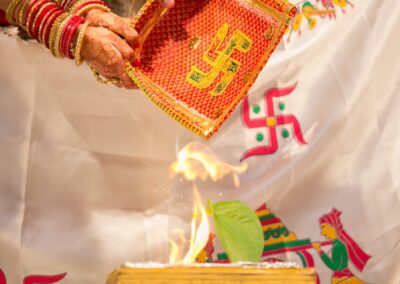 Hands hold a decorated tray with a swastika symbol over a small fire.