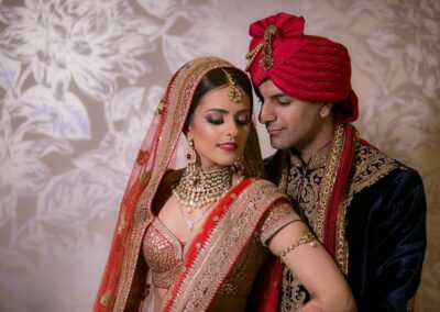 Bride and groom posing together in red and navy attire after ceremony.
