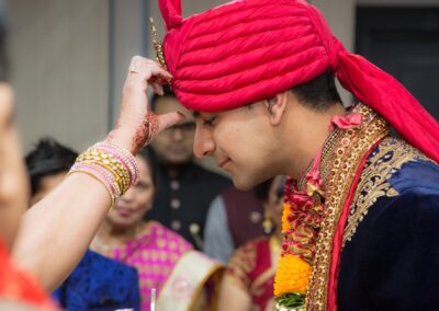 Groom receiving ceremonial tilak on forehead before Hindu wedding.
