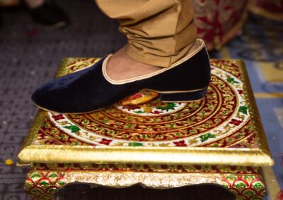 Groom’s velvet shoe on ornate golden wedding platform.