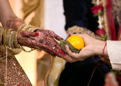 Bride receiving orange and betel leaf during Hindu wedding ritual.