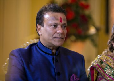 Man with red tilak attending Hindu wedding ceremony.
