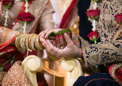 Bride and groom holding betel leaves together during Hindu ritual.