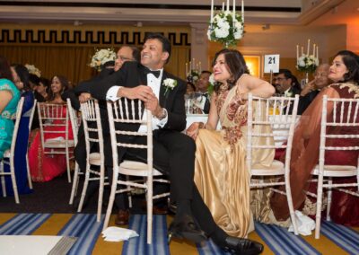 Guests seated at tables laughing and watching wedding speeches.