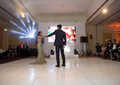 Couple performing their first dance on illuminated floor at wedding reception.