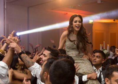 Bride lifted on guests’ shoulders dancing joyfully at the wedding party.