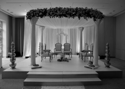Decorated Hindu wedding mandap with floral canopy, chairs, and ceremonial setup.