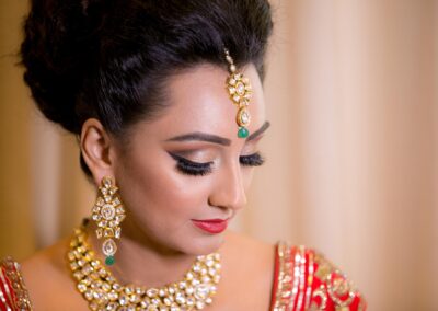 Bride looking down gracefully showing detailed bridal makeup and gold jewellery set.