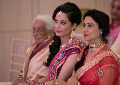 Three generations of women seated together watching the wedding ceremony.