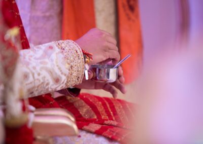 Groom stirring ritual mixture in silver bowl during Hindu marriage ceremony.