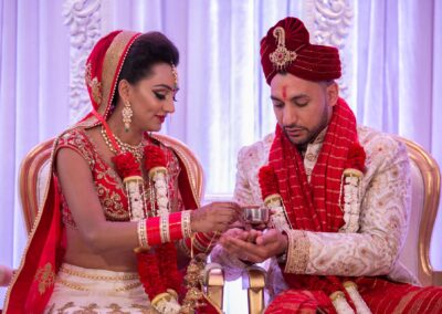 Bride offering ritual drink to groom during traditional Hindu wedding ceremony.