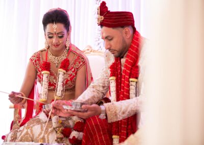 Bride and groom performing sacred wedding ritual with offerings during Hindu ceremony.