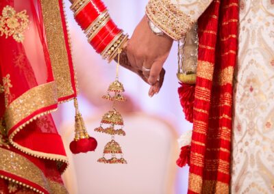 Bride and groom holding hands showing red bangles and golden kalire jewellery.