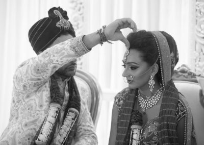 Groom applying sindoor to bride’s forehead during sacred wedding ritual ceremony.