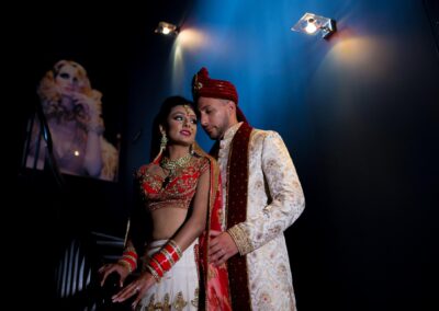 Couple in traditional Indian wedding attire sharing a romantic moment under soft lights.