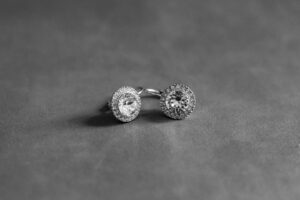 A pair of sparkling diamond stud earrings on a gray surface.