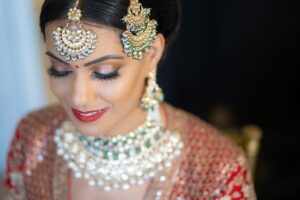 A close-up of a bride's face, focusing on her intricate jewelry and makeup.