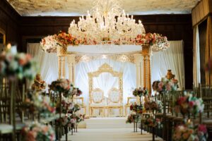 An empty wedding ceremony setup with an elaborate mandap and chandelier.