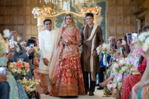 A bride and groom walk down an aisle with guests looking on.