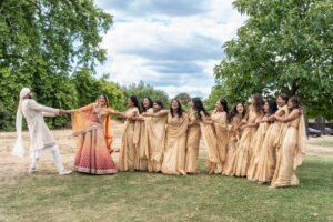A groom pulls a long line of laughing bridesmaids and the bride.